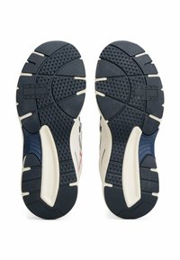 Scarpe sportive con suola in gomma che presenta un motivo testurizzato nero, una intersuola bianca e accenti blu sui lati. Il logo del marchio è visibile sulla suola.