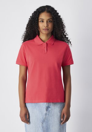 Polo rosso con colletto, patta con tre bottoni e maniche corte. Abbinato a una gonna di jeans azzurro chiaro. Tessuto dalla texture liscia.