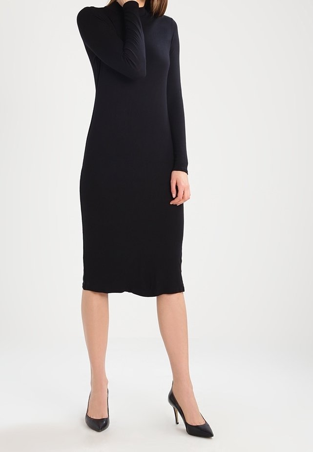 Schwarzes langärmliges Kleid in taillierter Form, knielang mit glatter Textur, kombiniert mit schwarzen high-heeled Schuhen.