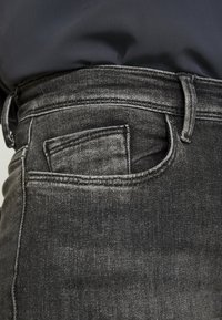 Svarta denimjeans med en klassisk design, framfickdetalj, rak passform och subtila blekningar över tygets textur.