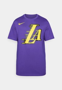 Fialové bavlněné tričko s kulatým výstřihem, které na přední straně obsahuje žlutou a černou grafiku "LA" a logo Nike na levém rameni.