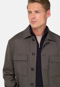 Chaqueta de mezcla de lana marrón con diseño de cuello, que presenta dos bolsillos en el pecho, botones negros y una capa interior con cremallera en color marino.