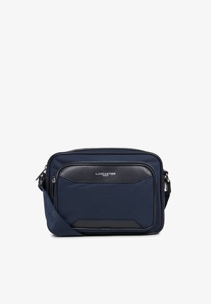 Sac messager marine avec une poche avant en cuir noir texturé et quincaillerie en argent. Dispose d'une sangle ajustable et de compartiments zippés.