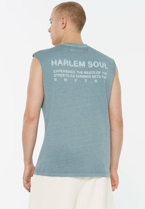 Ärmelloses blaues Baumwoll-T-Shirt mit Text auf der Rückseite, der lautet "HARLEM SOUL" und "ERLEBE DIE BEATS DER STRASSEN, WÄHREND DER SOMMER DEN RHYTHMUS BESTIMMT."