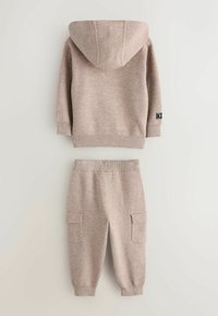 Beżowy dzianinowy hoodie z kapturem oraz ściągaczami na mankietach, sparowany z pasującymi joggerami z bocznymi kieszeniami i elastycznym pasem.
