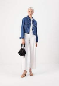 Jeans jakna, bela majica, belo visoko pasom široke hlače, bež sandale na peto i crna torbica s uzorkom i naboranim ručkama.