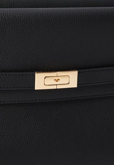 Bolsa de couro preta com uma textura suave e linhas horizontais. Possui um fecho em tom dourado com um design retangular e um branding discreto.