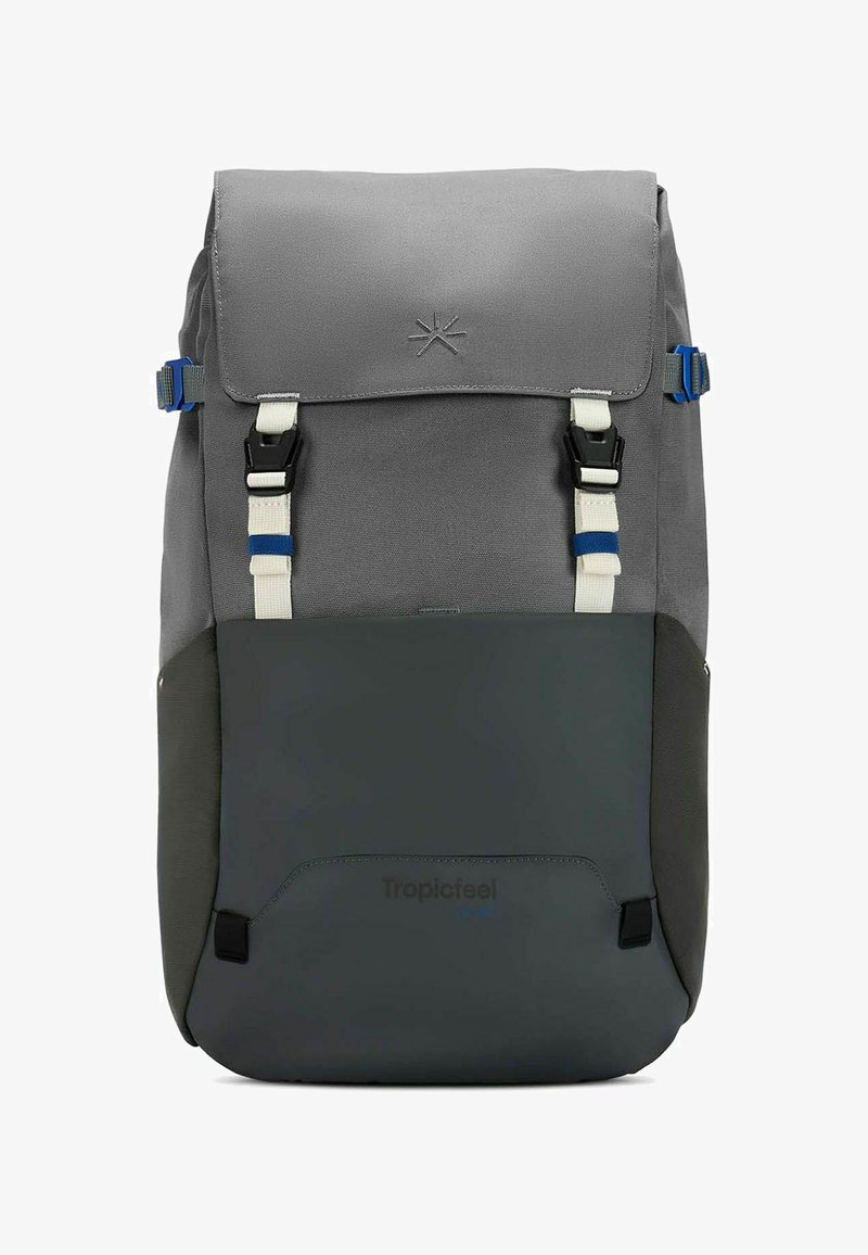 Mochila de tela gris con un diseño de parte superior enrollable, que cuenta con correas azules y blancas, un fondo gris oscuro y un logo impreso cerca de la base.
