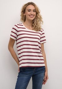Gestreept t-shirt met een ronde halslijn, korte mouwen en afwisselend bordeauxrode en crèmekleurige strepen op een zachte stof. Gecombineerd met een blauwe jeans.