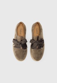 Scarpe in suede marrone con punta tonda, suola spessa e un grande fiocco di nastro scuro. All'interno marcate con "Gabor" e dettagli di taglia.