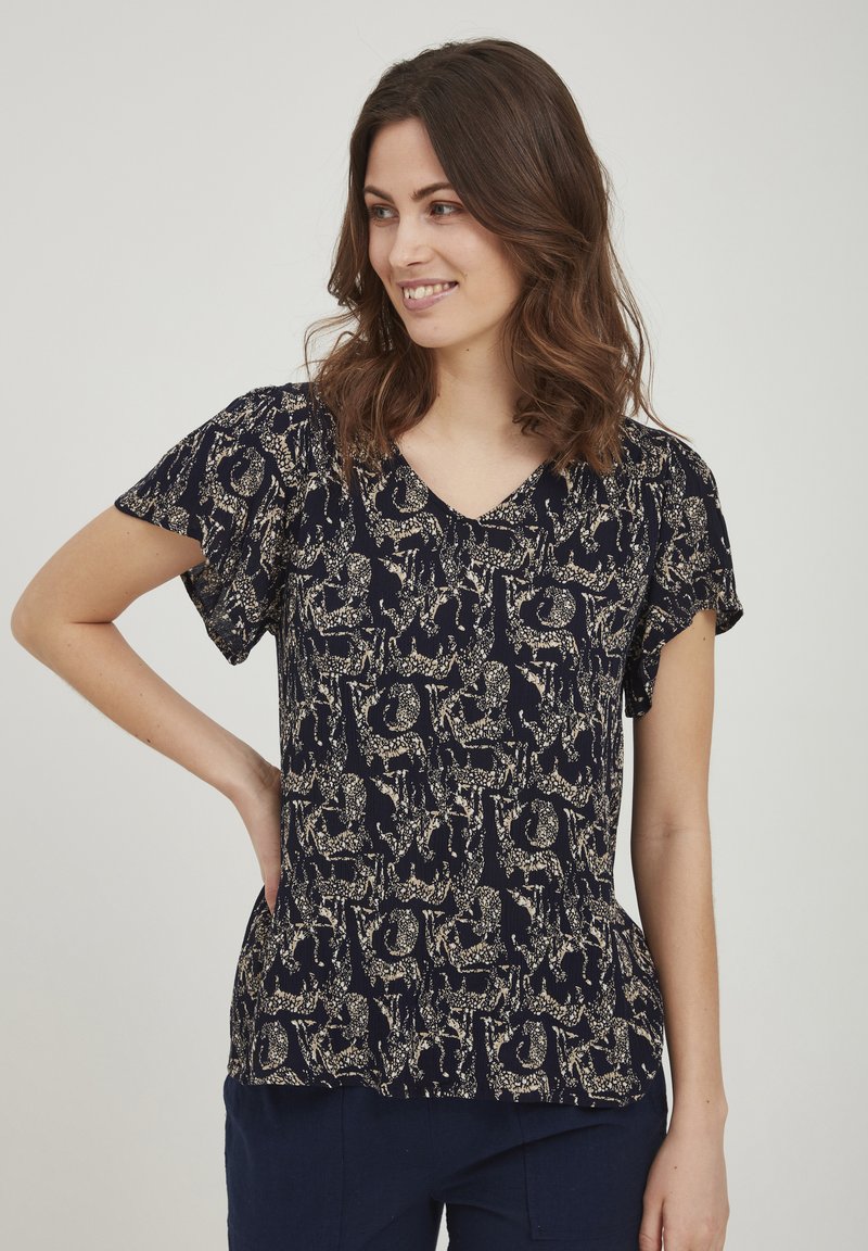 Blusa navy a maniche corte, scollo a V, e un tessuto strutturato con un motivo a fantasia animale dorato a contrasto. Vestibilità morbida con pieghe leggere.
