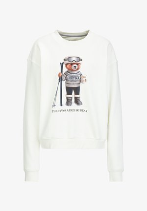 White sweatshirt featuring a graphic of a bear in skiing attire, holding skis and a drink. Text reads "CORTINA" and "THE 19V69 APRÈS SKI BEAR."