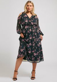 Svart blommig klänning med kall axel-design, långa ärmar och knytmidja. Har lila och gröna blommönster på lättviktig tyg.