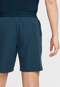 Marinblå shorts med mjuk textur, elastisk midjeresår och sidofickor. Designen är ledig med en slät yta.