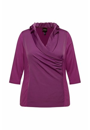 Paarse top met driekwart mouwen, voorzien van een gedrapeerde col en zijruche. Gladde stof met een lichte glans.