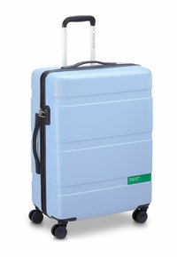 Hard-shell light blue suitcase with textured surface, black zipper and handle, four black wheels, and a green logo accent.