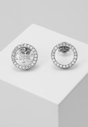Boucles d'oreilles clous rondes en argent avec des cristaux transparents autour des bords et un motif découpé décoratif au centre d'une boucle.