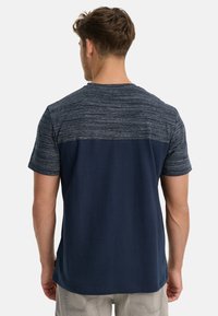 Kürzärmliges T-Shirt in Marineblau mit einem strukturierten Stoff, der ein gestreiftes Muster im oberen Rückenbereich und eine einfarbige Fläche darunter aufweist.
