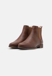 Bottes de cheville en cuir marron avec une texture lisse, des panneaux latéraux élastiques et un petit talon carré. Intérieur doublé pour plus de chaleur.