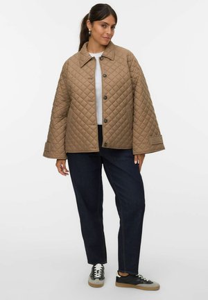 Quilted tan jacket with a collar, button front, and oversized sleeves. Paired with dark blue jeans and black sneakers with white laces.