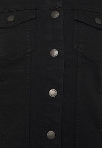 Czarna denimowa kamizelka z pionowym zapięciem na guziki z metalowymi guzikami w kolorze srebrnym, dwiema kieszeniami na piersi i teksturowanym wykończeniem.