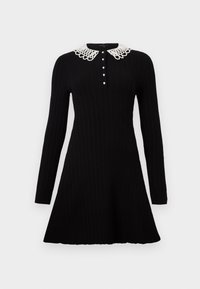 Robe noire en maille à manches longues avec jupe évasée, col Peter Pan en dentelle blanche et une rangée de petits boutons blancs sur le devant.