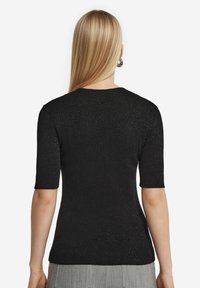 Svart kortärmad tröja gjord av textilt, metalliskt tyg med en slimmad design, rund halsringning och snyggt avslut vid nederkanten.