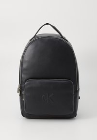 Black leather backpack with rounded shape, silver zipper, front pocket, embossed logo, and top handle for carrying.