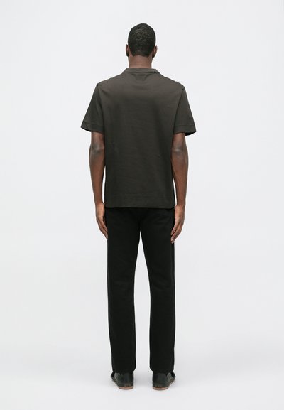 Cămașă scurtă, de culoare maro închis, cu croială dreaptă, asortată cu pantaloni negri. Design simplu, textură netedă și fără modele sau accente vizibile.