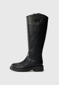 Botte noire en cuir montante, avec un bout arrondi, une semelle épaisse, des coutures minimalistes et un accent de logo à l'arrière. Texture lisse.
