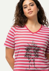 Rood-en-witte gestreepte T-shirt met korte mouwen en V-hals, voorzien van een illustratie van een zwarte veren vogel en de tekst "wees vriendelijk." Zacht materiaal.