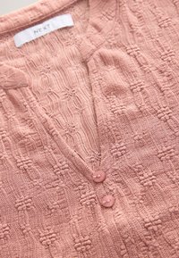 Cardigan tricoté texturé rose avec deux boutons et un col intérieur de vêtement à motif dentelle étiqueté "NEXT".