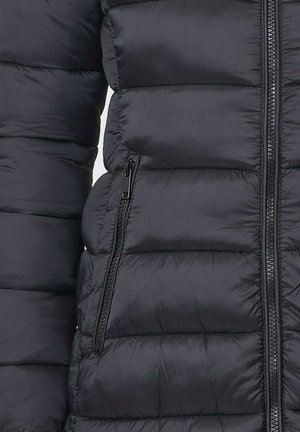 Veste en duvet noire avec un design matelassé horizontal, dotée d'une poche zippée et d'une texture lisse. Matériau léger et isolant.