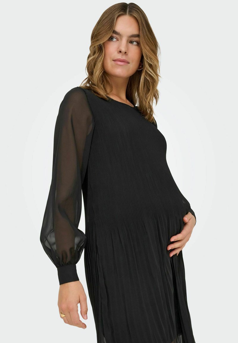 Črna midi obleka s plisirano teksturo in prosojnimi, napihnjenimi rokavi. Mehka, tekoča tkanina in sproščen kroj, zasnovan za nosečniško nošenje.