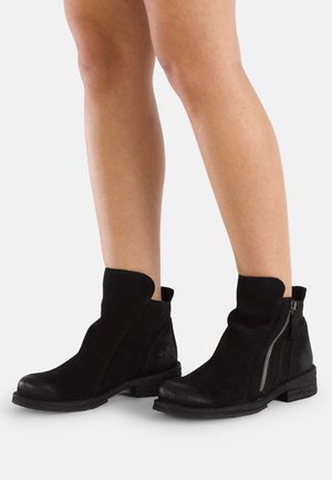 Bottines en daim noir avec un bout arrondi, fermeture éclair sur le côté et un talon texturé. Dotées d'un design de découpe unique sur le haut.