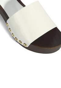 Witte gepatenteerde leren slide sandaal met een dikke band, voorzien van gouden studs aan de zijkant, en een bruine houten plateauzool.