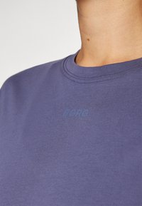 Fialové bavlněné tričko s kulatým výstřihem, na hrudi s nenápadným logem "BORG" ve světlejším odstínu. Měkká textura, ležérní design.