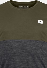 Olivgrünes und dunkelgraues Kurzarm-T-Shirt mit Rundhalsausschnitt, strukturiertem Stoff und einem weißen Logo auf der oberen linken Seite.
