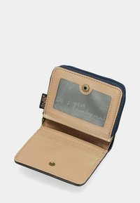 Kompakte Geldbörse mit einem beige Lederaußenbereich und einem navy Reißverschluss. Verfügt über ein klares Ausweisfenster und mehrere Kartenfächer. Messingschnappverschluss.