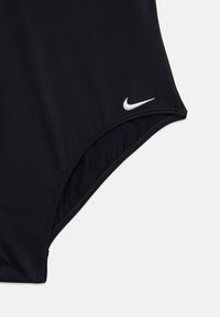 Svart badedrakt i ett stykke laget av glatt stoff med h�øyt kutt og sømmer. Har en liten hvit Nike-logo nær hoften.
