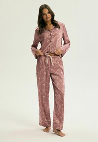 Jedwabny różowy zestaw piżamowy z koszulą zapinaną na guziki i spodniami na sznurki, ozdobiony złotym kwiatowym wzorem i lamówkami.