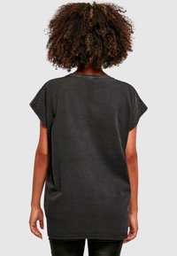 Čierne oversized tričko s krátkymi rukávmi, okrúhlym výstrihom a viditeľnými švami. Mäkko štruktúrovaná bavlnená tkanina.