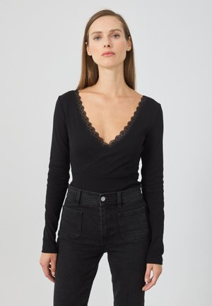 Zwarte lange mouw top met een diepe V-hals en kantafwerking. De stof is geribbeld en heeft een wikkelontwerp dat goed samengaat met strakke zwarte jeans.