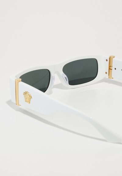 Lunettes de soleil blanches avec des verres foncés, finition texturée, accents en matériel doré proéminents et détail de logo sur le côté.
