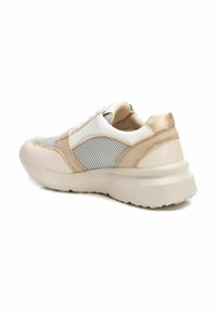 Zapatillas en color beige y blanco con materiales de malla y cuero. Forma redondeada, superficies texturizadas y una suela gruesa con un ligero tacón.