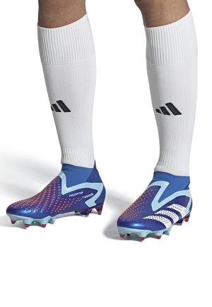 Blue soccer cleats with red dot patterns, white accents, and a textured surface. Paired with white socks featuring a black logo.
