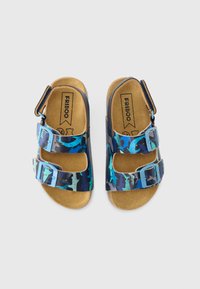 Sandálias azuis com padrão de camuflagem e duas fivelas ajustáveis; palmilha de cortiça e parte superior sintética. Sola plana com design leve.