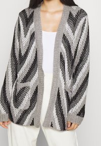 Cardigan à motifs gris et noirs avec ouverture devant, manches longues et poches latérales. Confectionné en tissu tricoté texturé.