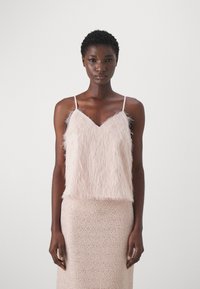 Camicetta fuzzy rosa chiaro con spalline sottili, abbinata a una gonna beige texturizzata e luccicante. Entrambi i capi presentano finiture morbide.