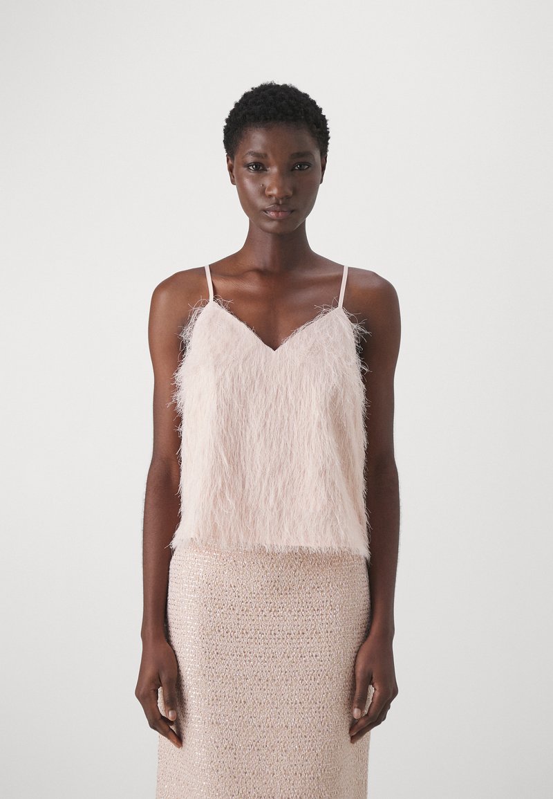 Camicetta fuzzy rosa chiaro con spalline sottili, abbinata a una gonna beige texturizzata e luccicante. Entrambi i capi presentano finiture morbide.